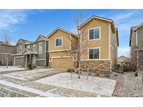 Tan two-story home with a stone accent, attached two-car garage, and a driveway with sidewalk out front at 4733 S Wenatchee Cir, Aurora, CO 80015