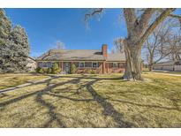 Charming brick home with a mature tree in the front yard and a pathway leading to the front door at 13 Wedge Way, Littleton, CO 80123