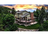 Stunning two-story home featuring a spacious deck, lush landscaping, and mountain views at sunset at 3254 Red Tree Pl, Castle Rock, CO 80104