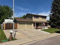 Charming two-story home with a well-manicured lawn, a two-car garage and mature trees at 4827 S Lewis Ct, Littleton, CO 80127