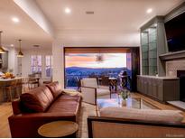 Comfortable living room boasts hardwood floors, a fireplace, and sliding doors to an outdoor patio with mountain views at 16671 Red Cliff Cir, Morrison, CO 80465