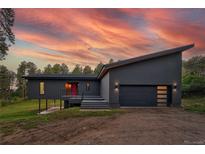 Modern home featuring sleek architecture, dark gray siding and an asymmetrical roof line, set against a vibrant sky at 20525 Flint Ln, Morrison, CO 80465