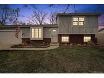 Charming two-story home featuring brick accents, a well-manicured lawn, and an inviting front entrance at dusk at 11125 W Alamo Pl, Littleton, CO 80127