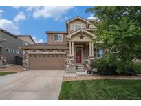 Charming two-story home featuring a stone facade, covered porch with star detail, and attached two-car garage at 7877 E 139Th Pl, Brighton, CO 80602