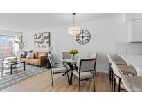 Bright dining area featuring a glass table, stylish chairs, and contemporary lighting, connecting seamlessly to the living area at 1818 S Quebec Way # 2-3, Denver, CO 80231
