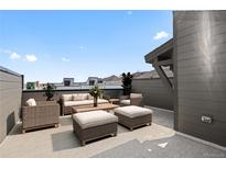 A luxurious rooftop patio featuring wicker furniture, including a sofa, chairs, ottomans, and a coffee table at 14412 Pansy Loop, Morrison, CO 80465