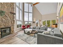 Bright living room featuring a stone fireplace, large windows, and vaulted ceilings at 30382 Marys Dr, Conifer, CO 80433