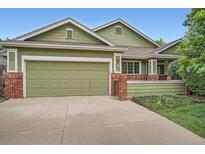 Charming green home featuring a two-car garage and brick accents at 1851 S Marshall Cir, Lakewood, CO 80232