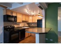 Well-lit kitchen featuring wooden cabinets, modern appliances, and a convenient breakfast bar at 655 N Pearl St # 208, Denver, CO 80203