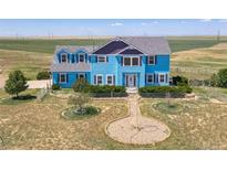 Two-story light blue house with landscaping and a long driveway at 8441 Flint Ridge St, Bennett, CO 80102