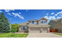 Charming two-story home with a well-manicured lawn and a three car garage at 17826 E Cloudberry Dr, Parker, CO 80134