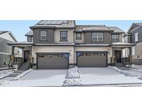 Two-story townhome showcasing attached garages, dark trim, and solar panels at 537 Nightsky St, Erie, CO 80516