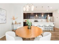 Modern kitchen featuring dark cabinets, stainless steel appliances, and a white countertop island with seating at 6041 N Orleans St, Aurora, CO 80019