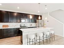 A modern kitchen featuring dark cabinets, quartz countertops, stainless steel appliances, and pendant lighting at 6041 N Orleans St, Aurora, CO 80019