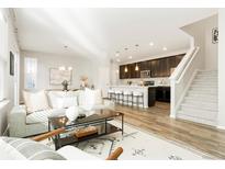 Bright, open floor plan showcases a modern living room flowing into the kitchen and dining area at 6041 N Orleans St, Aurora, CO 80019