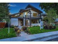 Contemporary two-story home with a modern design, balcony, manicured lawn, and walkway with landscape lighting at 1175 S Jackson St, Denver, CO 80210