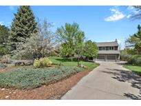 Charming gray two-story home with a well-maintained lawn, mature trees, and a spacious driveway at 7605 E Windlawn Way, Parker, CO 80134