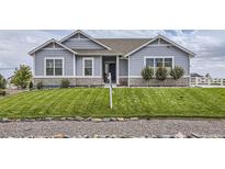 Ranch style home with gray siding, stone accents, and a landscaped lawn at 16122 Emporia Way, Brighton, CO 80602