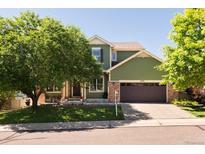 Charming two-story home with green siding, brick accents, well-manicured lawn, and a two-car garage at 2214 E 101St Ave, Thornton, CO 80229