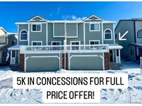 Gray townhome exterior with two-car garage, snowy landscape, and winter light at 1444 Willow Oak Rd, Castle Rock, CO 80104