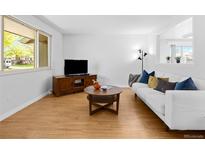 Inviting living room with hardwood floors, modern TV, white couch, and decorative pillows, perfect for relaxation at 4779 S Owens Way, Littleton, CO 80127