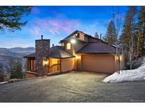 Beautiful exterior with stone accents, a spacious driveway, and scenic mountain views at sunset at 29011 Upper Moss Rock Rd, Golden, CO 80401