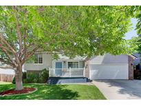 Charming two-story home with a light blue door, white porch railing and a mature tree in the front yard at 647 Florence Ave, Firestone, CO 80520