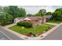 Charming brick home featuring a well-maintained lawn, mature trees, and a detached two-car garage at 920 Emerson Cir, Northglenn, CO 80233