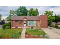 Charming brick home featuring a manicured lawn, complemented by mature trees, and a cozy front entrance at 920 Emerson Cir, Northglenn, CO 80233