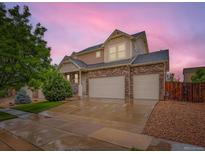 Beautiful two-story home with a three-car garage and stone accents under a lovely pink sky at 10570 Worchester Dr, Commerce City, CO 80022