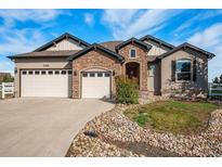 Charming two-story home featuring a stone facade, three-car garage, and well-manicured landscaping at 7998 Faith Ct, Frederick, CO 80530