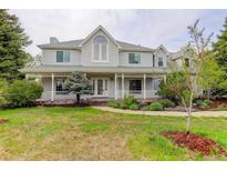 Inviting two-story home with a charming front porch, mature trees, and a well-manicured lawn at 31 N Algonquian St, Aurora, CO 80018