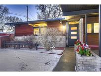 Mid-century modern home with wood siding, covered entry, and landscaped yard at 6127 S Westview St, Littleton, CO 80120