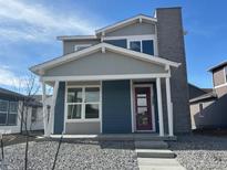 Charming two-story home with a covered porch, gray and blue siding and stone chimney at 2267 Peregrine Dr, Brighton, CO 80601