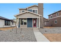 Charming two-story home with a blue and gray exterior, complemented by a well-maintained, xeriscaped front yard at 2267 Peregrine Dr, Brighton, CO 80601