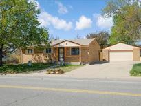 Charming brick home with a detached garage and a well-manicured front yard on a sunny day at 11937 Claude Ct, Northglenn, CO 80233