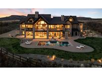 Stunning multi-story home with a pool and luxurious outdoor seating under a colorful sunset sky at 3148 Keep Dr, Sedalia, CO 80135