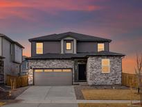 Charming two-story home boasts stone accents, a two-car garage, and a well-manicured lawn at 6091 Sugarloaf St, Brighton, CO 80601