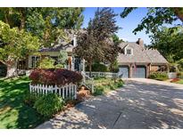 Charming home featuring a lush front yard, mature trees, and a welcoming entrance with a white picket fence and driveway at 7001 S Newport St, Centennial, CO 80112