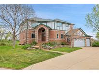 Two-story brick home with landscaped front yard, driveway, and attached garage at 3970 Pierson St, Wheat Ridge, CO 80033