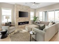 Bright living room featuring a stone fireplace, sleek TV, and comfortable seating area at 6530 Barnstead Dr, Castle Pines, CO 80108