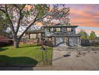 Charming two-story home with a lush front yard and a two-car garage at sunset at 4933 S Xenon Ct, Morrison, CO 80465
