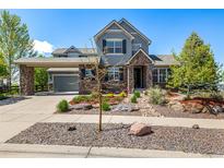 Charming two-story home with stone accents, a covered entrance, professional landscaping, and an attached two-car garage at 11857 S Saunter Ln, Parker, CO 80138