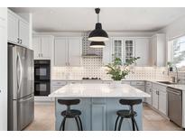 Bright kitchen features white cabinets, stainless steel appliances, and an island with barstool seating at 25362 E Indore Dr, Aurora, CO 80016