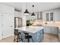 Well-lit kitchen featuring stainless steel appliances, white cabinets, and blue island with bar seating at 25362 E Indore Dr, Aurora, CO 80016