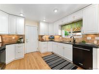 Traditional kitchen with white cabinetry, black countertops, and stainless steel appliances at 8475 W 74Th Dr, Arvada, CO 80005