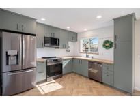 Updated kitchen features gray cabinets, butcher block counters, and stainless steel appliances at 9272 E Mansfield Ave, Denver, CO 80237