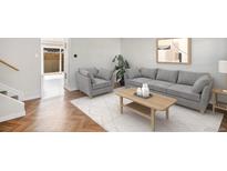 Bright living room with wood floors, gray sofa and chair, art, and a decorative coffee table at 9272 E Mansfield Ave, Denver, CO 80237