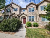 Charming townhome with stone accents, a manicured lawn, and a welcoming front entrance at 12753 Ivanhoe St, Thornton, CO 80602