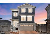 Charming home featuring stone accents, neutral siding, and a two-car garage, all set against a colorful sunset sky at 21925 E 44Th Pl, Aurora, CO 80019
